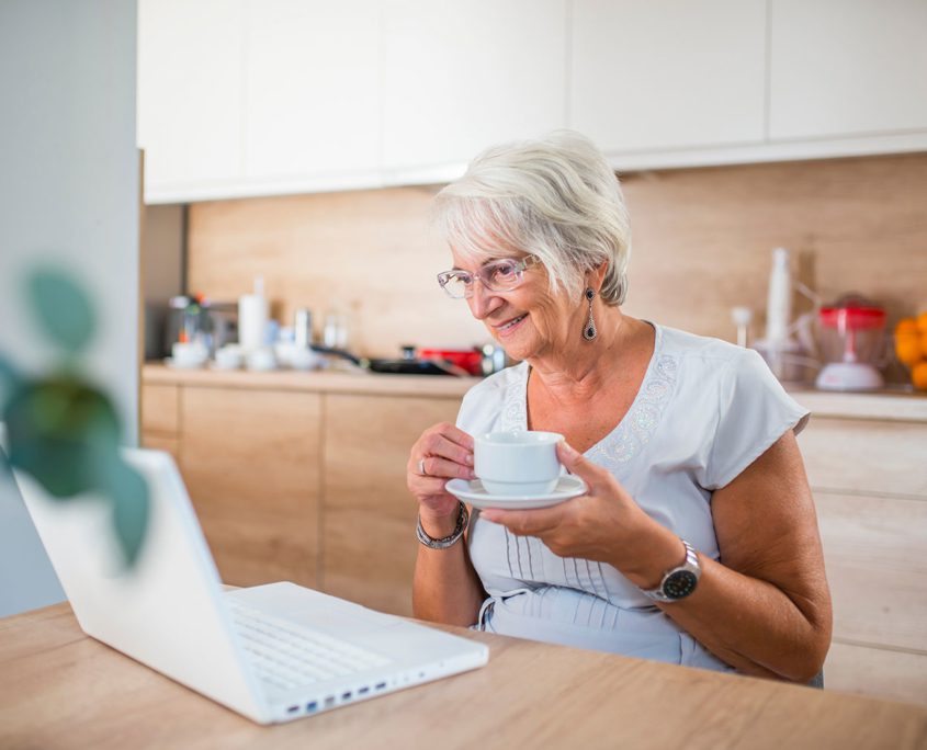 Woman looking at laptop drinking coffee