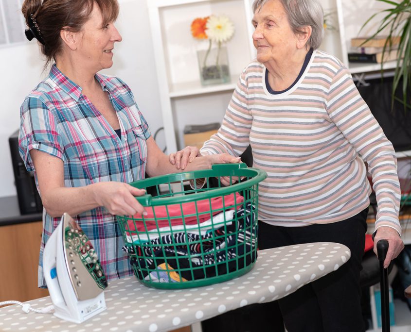 Younger woman helping elderly woman with ironing