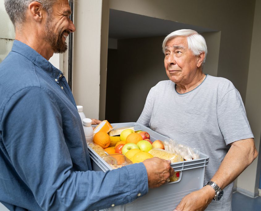 Man giving older adult a box of groceries